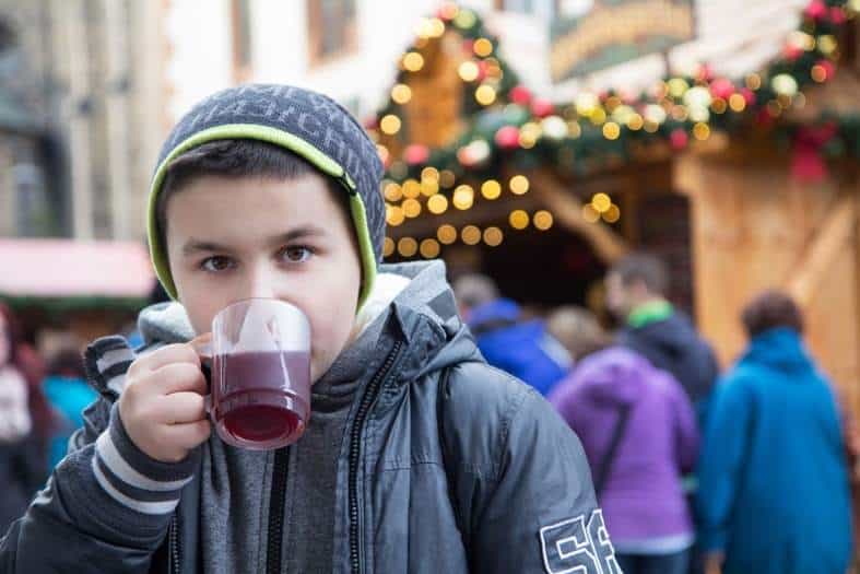 a teen boy enjoying a warm drink at a christmas market