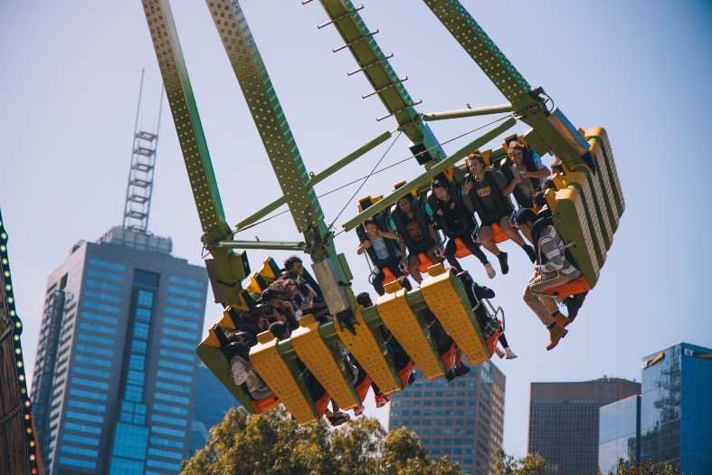 teenagers in Melbourne Australia on fast carnival ride with the city in the background