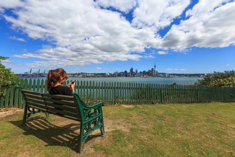 a young adult spending time on her phone on the north shore of Auckland