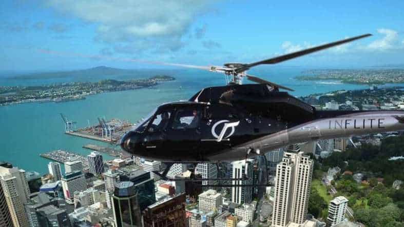 A helicopter flying over Auckland New Zealand with the bay and skyscrapers in the back ground