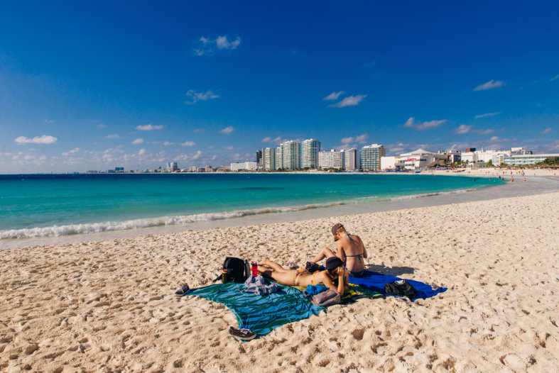 two teenage girls sunbaking in cancun mexico on a white sand beach