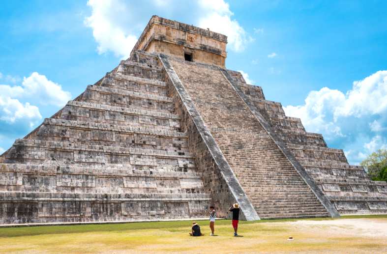 A young adult gettingn her photo taken infront of Chichen Itza