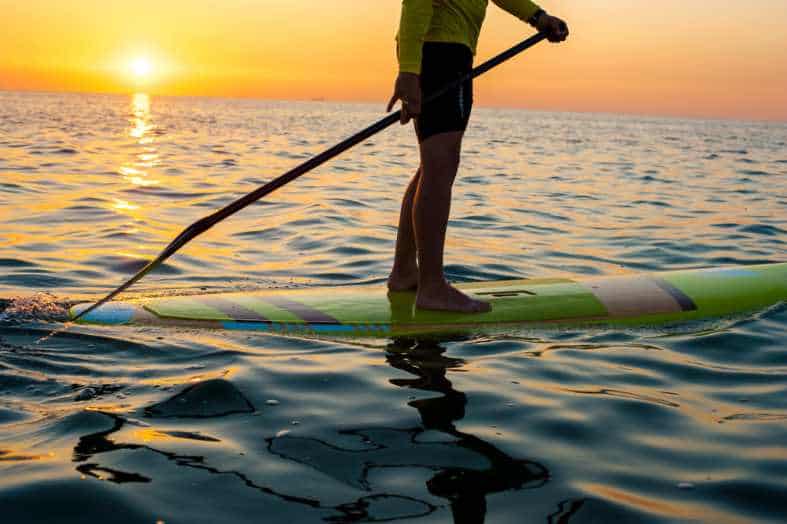 a teen boy enjoying paddle boarding in cancun at sunset
