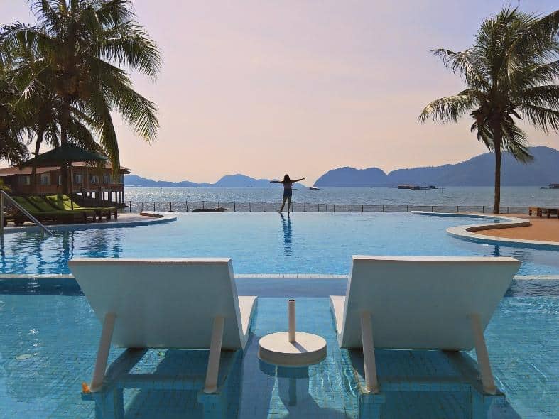 a tween girl in the pool in Langkawi with the ocean in the background