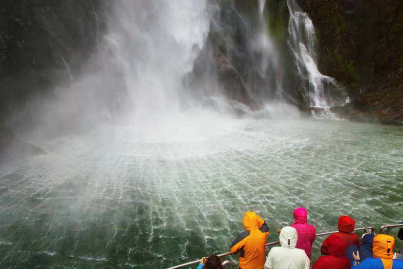 standing in front of a stunning waterfall in Milford Sound