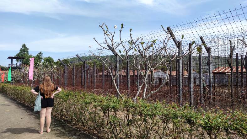 A somber scene at Phu Quoc Prison Camp, with rows of prison cells enclosed by high walls and barbed wire.