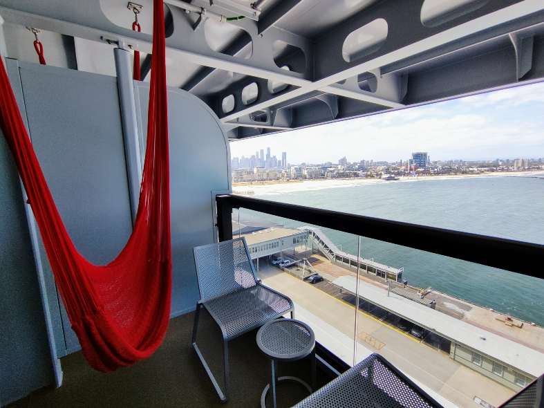 Interior of a cabin on Virgin Voyages' Resilient Lady, featuring a comfortable bed, modern decor, and a window with an ocean view.