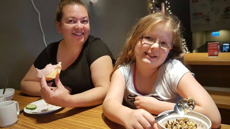 a mum and daughter having breakfast at a hotel. Having breakfast included in a hotel price is a great way to help with being able to afford the cost of travelling as a family