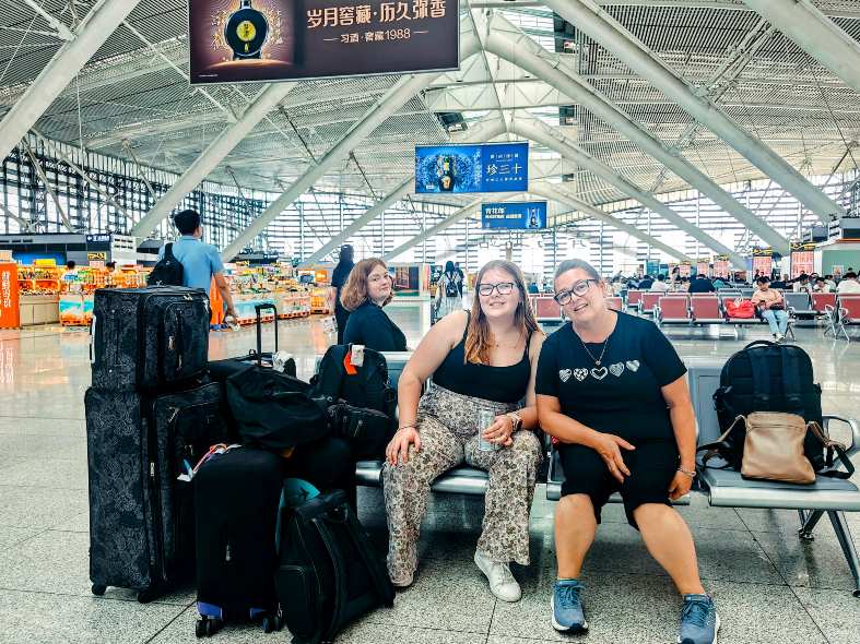 two women sitting on a bench in a terminal